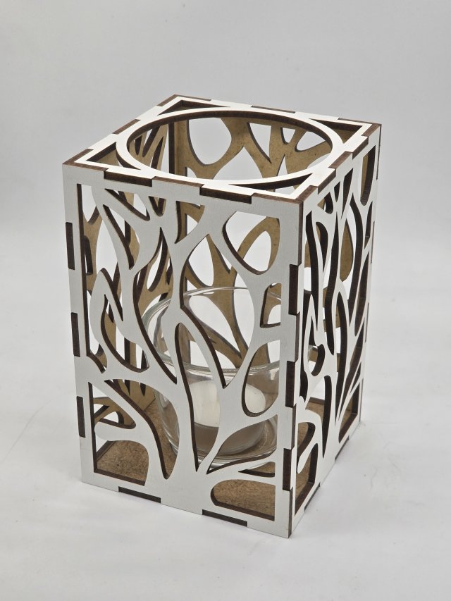 Ljuslyktan Eld i vit – handgjord trälykta med utskuret eld-motiv som sprider ett varmt och levande ljus. Tillverkad i Sverige av Nordland Design.