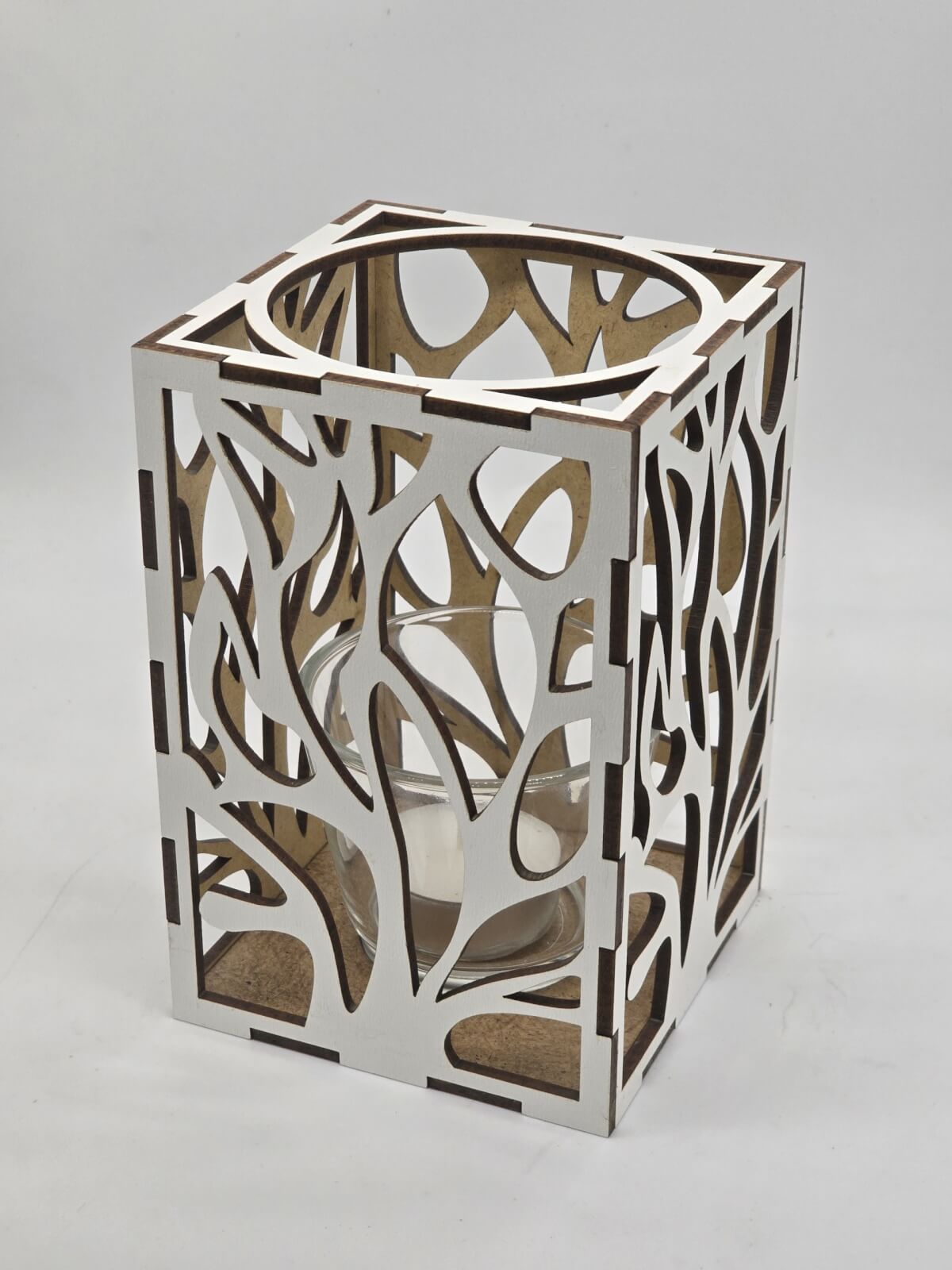 Ljuslyktan Eld i vit – handgjord trälykta med utskuret eld-motiv som sprider ett varmt och levande ljus. Tillverkad i Sverige av Nordland Design.