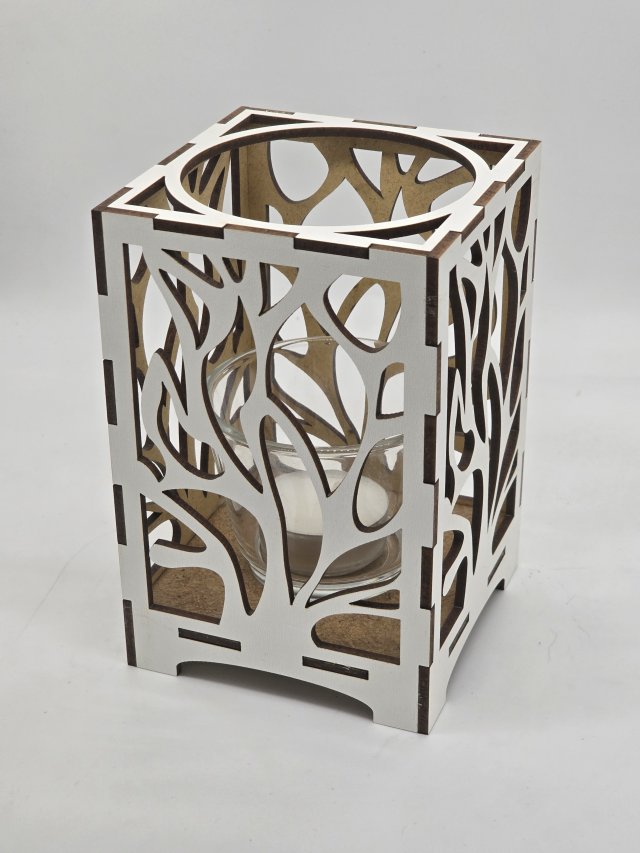 Ljuslyktan Eld i vit – handgjord trälykta med utskuret eld-motiv som sprider ett varmt och levande ljus. Tillverkad i Sverige av Nordland Design.