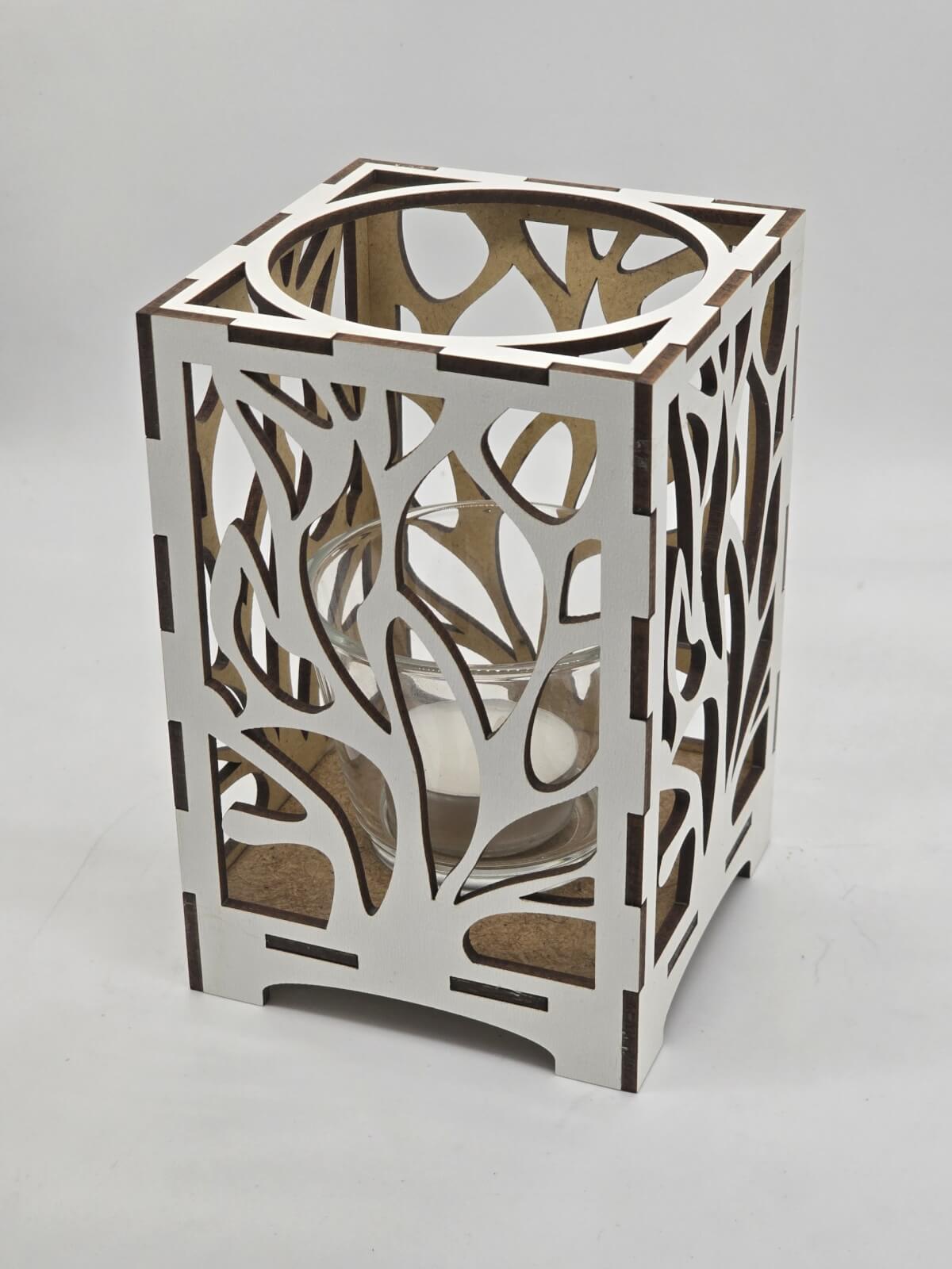 Ljuslyktan Eld i vit – handgjord trälykta med utskuret eld-motiv som sprider ett varmt och levande ljus. Tillverkad i Sverige av Nordland Design.