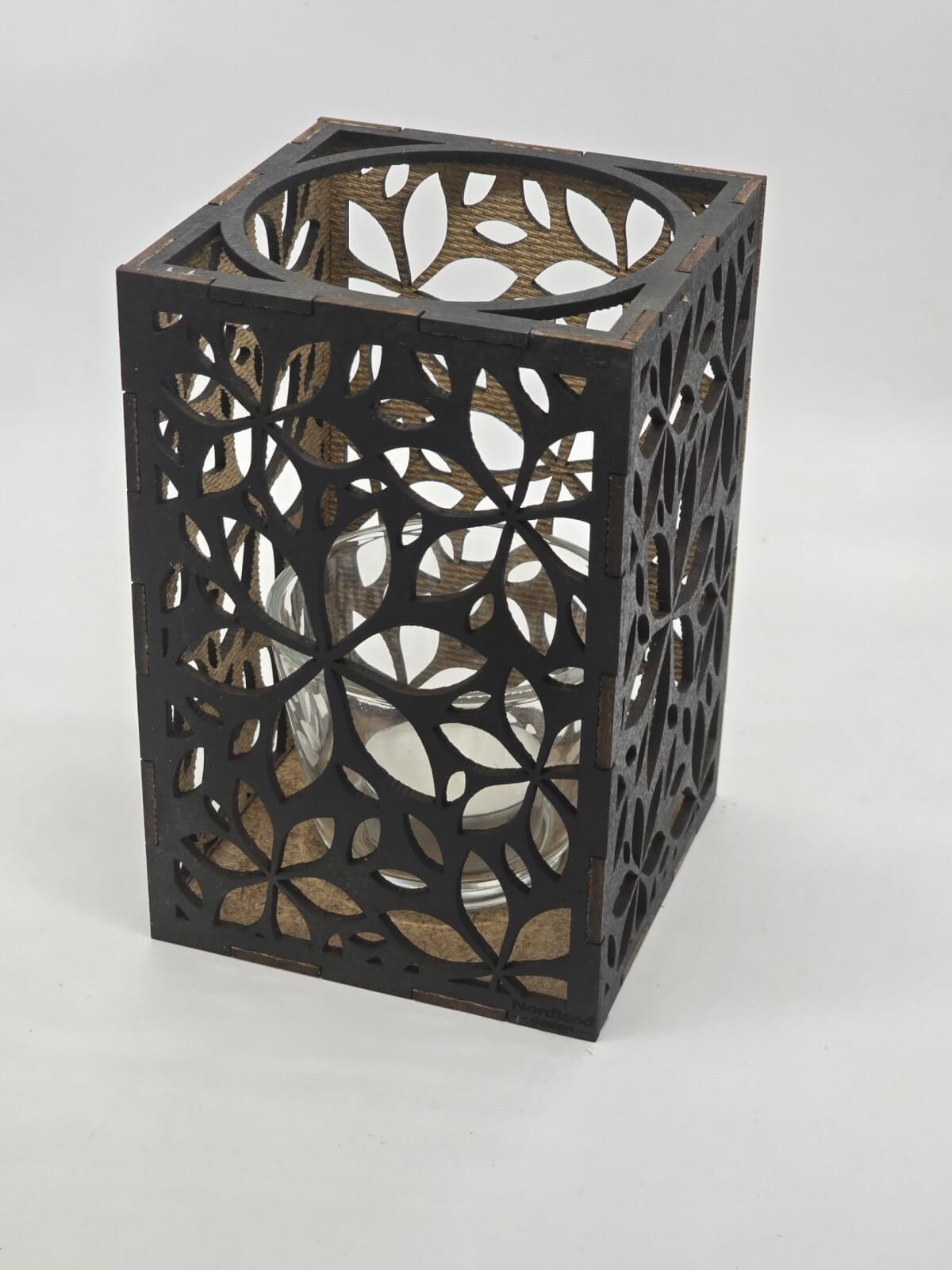 Ljuslyktan Lily i svart – handgjord trälykta med frostinspirerat mönster som sprider ett varmt och elegant ljus. Tillverkad i Sverige av Nordland Design.