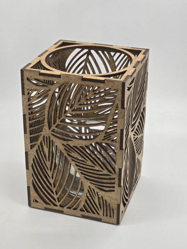 Ljuslyktan Saga i natur – handgjord trälykta med lövmotiv som skapar ett varmt och naturligt ljusspel. Svenskt hantverk från Nordland Design.