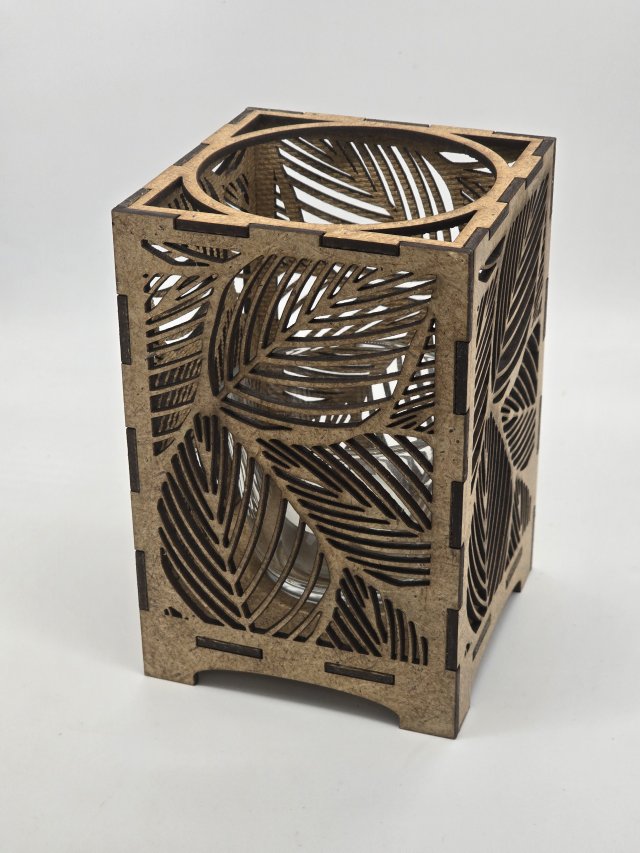 Ljuslyktan Saga i natur – handgjord trälykta med lövmotiv som skapar ett varmt och naturligt ljusspel. Svenskt hantverk från Nordland Design.