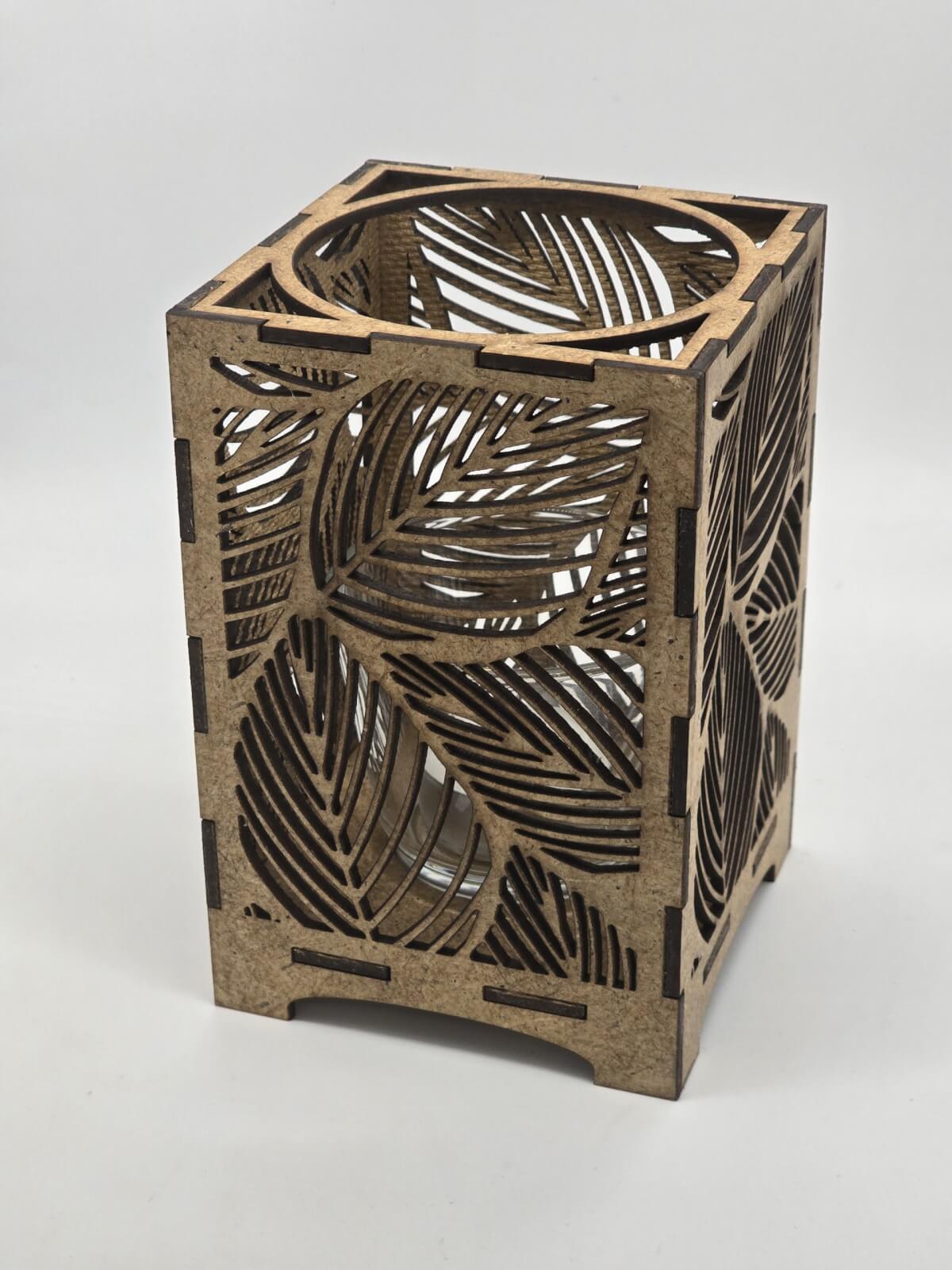 Ljuslyktan Saga i natur – handgjord trälykta med lövmotiv som skapar ett varmt och naturligt ljusspel. Svenskt hantverk från Nordland Design.